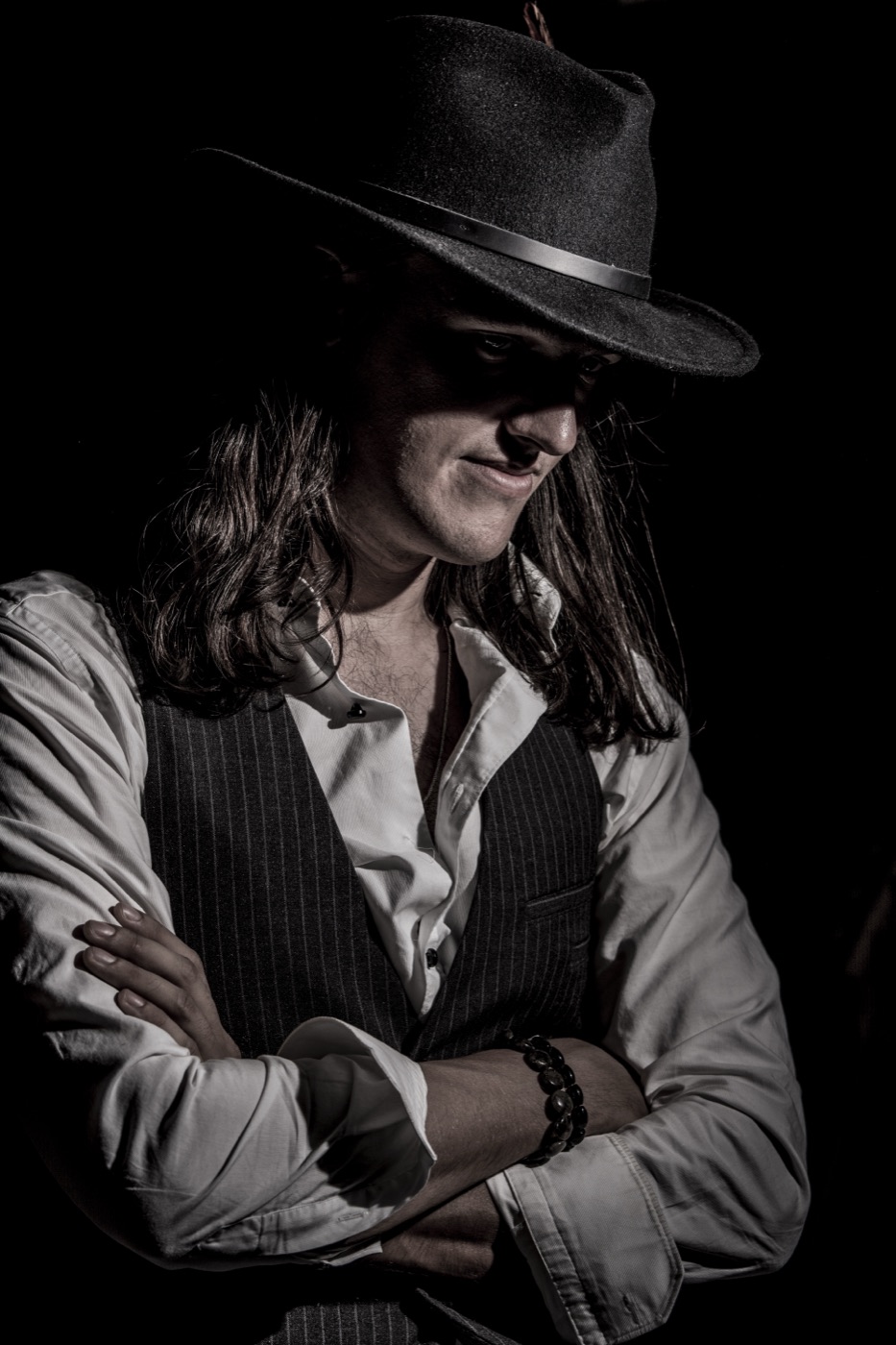 Detective 47 — arms crossed, fedora low, in the studio shadows